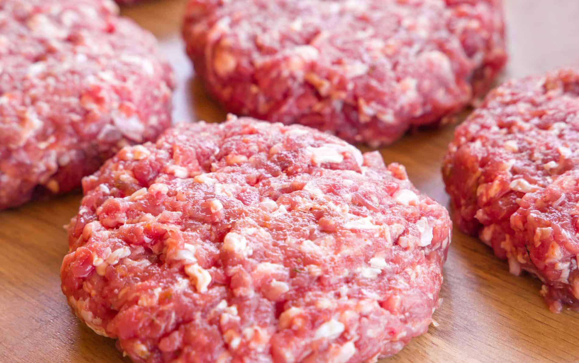 Raw Hamburger Patties On A Wooden Surface, Ready For Cooking.