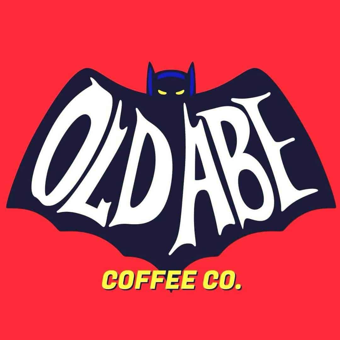 Logo With A Stylized Bat Shape Featuring The Text Old Abe In White And Coffee Co. In Yellow On A Red Background.